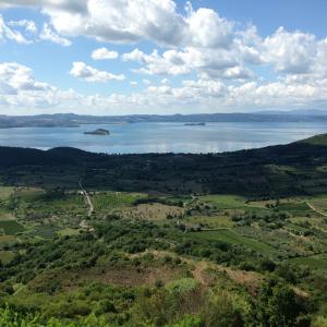 Vista panoramica di un lago con isole e campagna verdeggiante sotto un cielo nuvoloso.