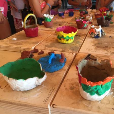 Laboratorio di ceramica con ciotole colorate create da bambini su tavoli di legno.