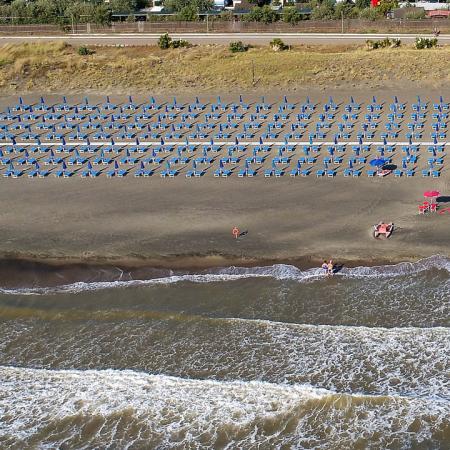 Spiaggia con file di ombrelloni blu e una torretta di salvataggio.