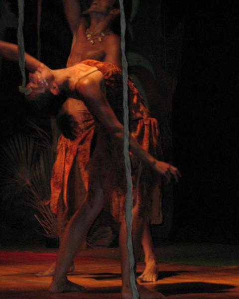 Due ballerini eseguono una danza tribale su un palco con sfondo artistico.