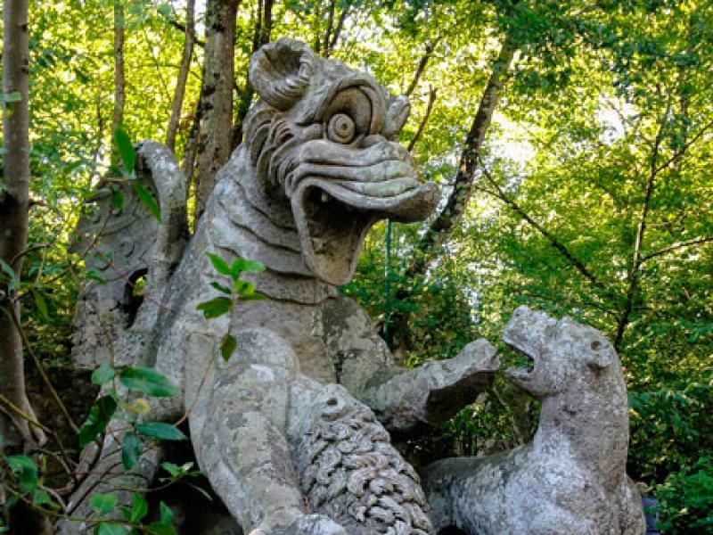 Scultura di drago e leone in un parco boschivo, atmosfera fiabesca.